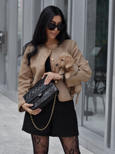 a lady in a camel cropped jacket with a black mini skirt